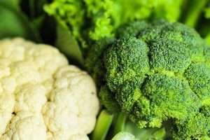 A close-up of broccoli and cauliflower, with dark green broccoli in the foreground and light cream cauliflower in the background