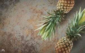 Two pineapples on a textured concrete wall
