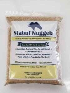 A clear bag of Stabul Nuggets horse feed with a blue horse head on the label, listing features such as balanced vitamins and minerals, low starch and sugar, and added probiotics