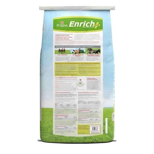 backside of a bag of Purina Enrich Plus horse feed in a light blue color with a white stripe. The bag has a picture of three horses and claims to be a 30+ day supply for growing and mature horses, low starch and low sugar. The background is a green field with blue sky